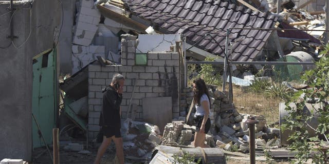People walk in a yard of a apartment building destroyed by Russian shelling on the outskirts of Odesa, Ukraine, Tuesday, July 26, 2022. 