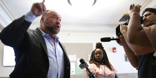 Alex Jones talks to media during a midday break during the trial at the Travis County Courthouse in Austin, Texas, Tuesday, July 26, 2022. 