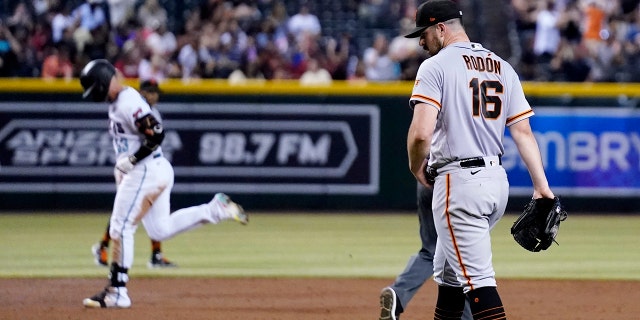 San Francisco Giants starting pitcher Carlos Rodon (16) walks around the mound after giving up a three-run home run to Arizona Diamondbacks' Christian Walker, left, during the third inning of a game on July 26, 2022, in Phoenix, Arizona.