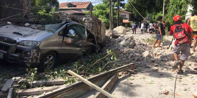 In this handout photo provided by the Philippine Red Cross, a vehicle is damaged as a wall collapses after a strong earthquake hit Ilocos Sur province, Philippines on Wednesday, July 27, 2022.