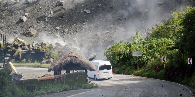 Boulders fall as a vehicle negotiates a road during an earthquake in Bauko, Mountain Province, Philippines on Wednesday, July 27, 2022.