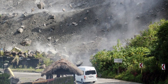 Boulders fall as a vehicle negotiates a road during an earthquake in Bauko, Mountain Province, Philippines on Wednesday, July 27, 2022.