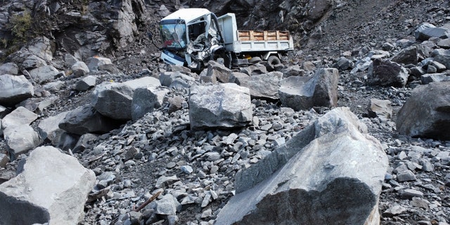 The damaged truck is lying beside a rock after an earthquake struck Bauco in Mountain Province, Philippines on Wednesday, July 27, 2022, falling along the road.