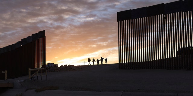 Migrant families from Brazil passing through a gap in the border wall after crossing from Mexico to Yuma, Arizona.