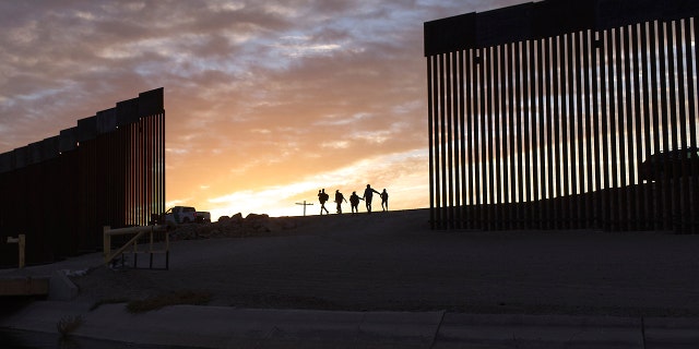 A pair of migrant families from Brazil pass through a gap in the border wall to reach the United States after crossing from Mexico to Yuma, Arizona, to seek asylum.