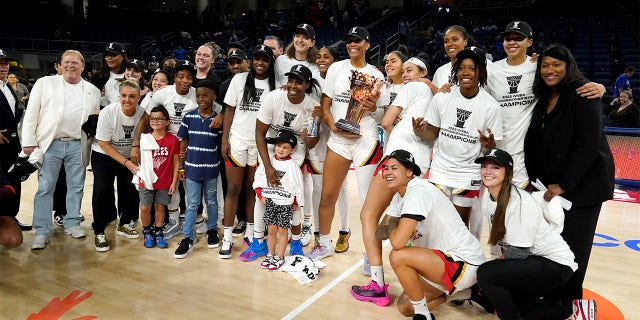 The Las Vegas Aces, with team owner Mark Davis, left, pose for a team photo after defeating the Chicago Sky in the WNBA Commissioner's Cup basketball game Tuesday, July 26, 2022, in Chicago. The Aces won 93-83.