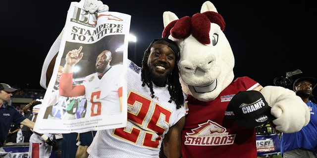 Bo Scarbrough #25 of the Birmingham Stallions poses with the Birmingham Stallions mascot after defeating the Philadelphia Stars 33-30 to win the USFL Championship game at Tom Benson Hall Of Fame Stadium on July 3, 2022 in Canton, Ohio.