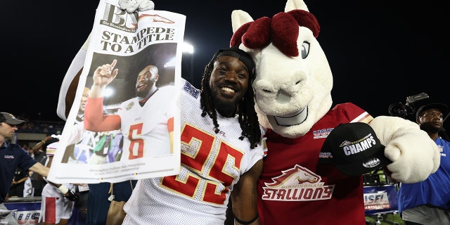 Bo Scarbrough #25 of the Birmingham Stallions poses with the Birmingham Stallions mascot after defeating the Philadelphia Stars 33-30 to win the USFL Championship game at Tom Benson Hall Of Fame Stadium on July 03, 2022 in Canton, Ohio.