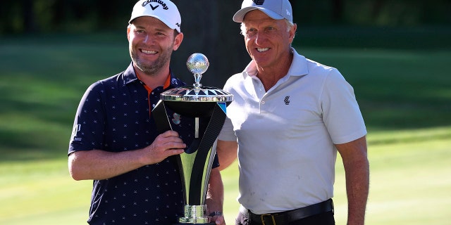 Branden Grace (left) and LIV Golf CEO Greg Norman (right) hold the trophy after Grace's victory at the Portland Invitational LIV Golf Tournament in North Plains, Oregon, Saturday, July 2, 2022. posing. 