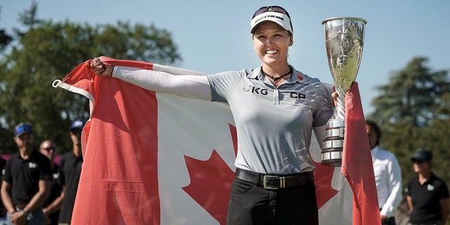 Brooke Henderson, of Canada, celebrates with her trophy after winning the Evian Championship women's golf tournament in Evian, eastern France, Sunday, July 24, 2022. 