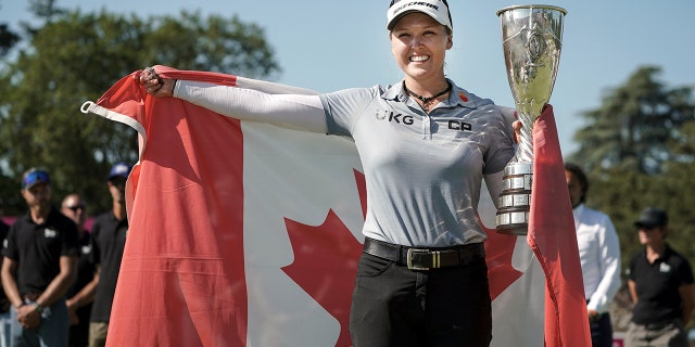 Brooke Henderson, of Canada, celebrates with her trophy after winning the Evian Championship women's golf tournament in Evian, eastern France, Sunday, July 24, 2022. 