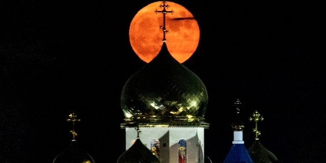 The full "Buck" moon rises behind the Russian Orthodox Church of the Apostle Andrew and all Russian saints, in the village of Episkopeio, about 23 kilometres southwest of Cyprus' capital, on July 24, 2021. 