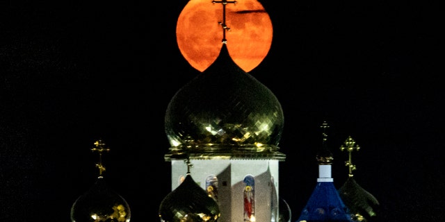 The full "Buck" moon rises behind the Russian Orthodox Church of the Apostle Andrew and all Russian saints, in the village of Episkopeio, about 23 kilometres southwest of Cyprus' capital, on July 24, 2021.