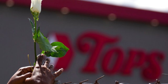 Cariol Horne, 54, places a rose on the fence outside the Tops Friendly Market Thursday, July 14, 2022, in Buffalo, N.Y.