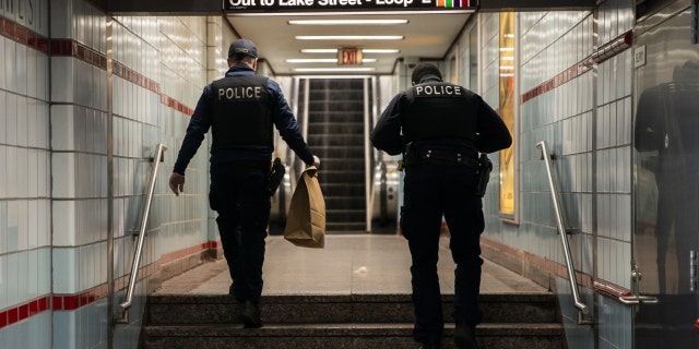 Chicago police officers walk through the CTA Red Line State/Lake station while working the scene where a 27-year-old man and 55-year-old man were shot on the 100 block of North Wabash in the Loop, Sunday, May 1, 2022, in Chicago. 