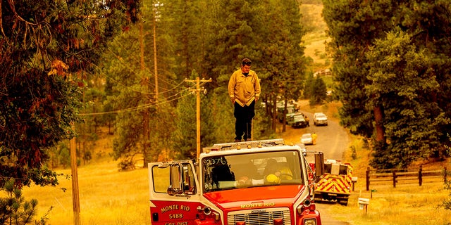 A firefighter stands atop a fire engine shortly after coming on duty to battle the Oak Fire in the Jerseydale community of Mariposa County, California, on Sunday, July 24, 2022.