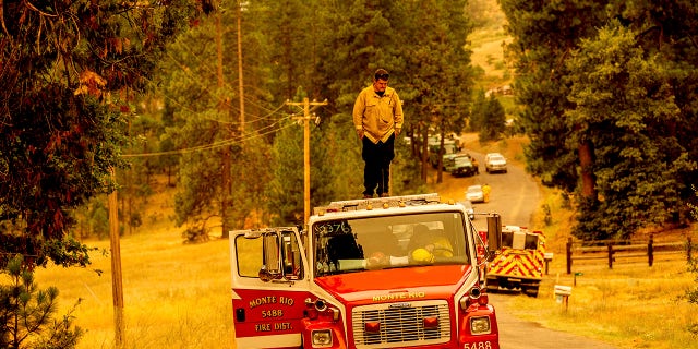 A firefighter stands atop a fire engine shortly after coming on duty to battle the Oak Fire in the Jerseydale community of Mariposa County, California, on Sunday, July 24, 2022.