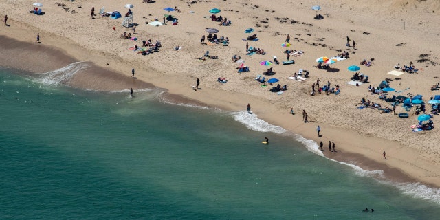 Beachgoers refrain from venturing too far out into the water at the Cape Cod National Sea Shore in Cape Cod, Massachusetts on July 15, 2022.