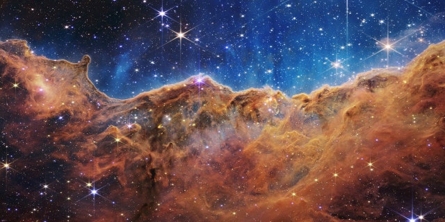 What looks a lot like rocky mountains on a moonlit evening is actually the edge of the nearby, young star-forming region NGC 3324 in the Carina Nebula.  Taken in infrared light by the Near Infrared Camera (NIRCam) on NASA's James Webb Space Telescope, this image reveals previously obscured regions of star birth.