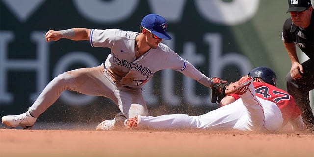 Toronto Blue Jays' Cavan Biggio, left, tags out Boston Red Sox's Yolmer Sanchez, right, who was attempting to steal second base in the fourth inning of a baseball game, Sunday, July 24, 2022, in Boston. 