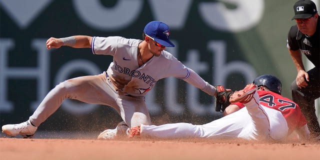 Toronto Blue Jays' Cavan Biggio, left, tags out Boston Red Sox's Yolmer Sanchez, right, who was attempting to steal second base in the fourth inning of a baseball game, Sunday, July 24, 2022, in Boston.