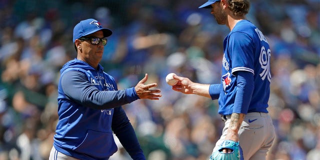 Toronto Blue Jays pitcher Adam Cimber, right, is pulled by manager Charlie Montoyo, left, during the eighth inning of a baseball game against the Seattle Mariners, Sunday, July 10, 2022, in Seattle. The Mariners won 6-5.