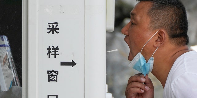 A man gets a throat swab at a testing site as people are required for a negative COVID test in the last 72 hours before entering some buildings and using public transportation in Beijing, Tuesday, July 19, 2022.