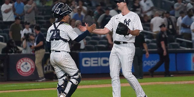New York Yankees catcher Jose Trevino, left, slap hands with relief pitcher Clay Holmes (35) after the team's win over the Tampa Bay Rays in a baseball game Tuesday June 14, 2022, in New York.
