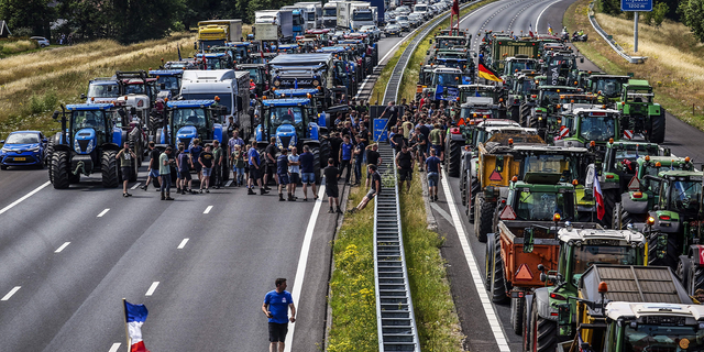 Farmers gather with their vehicles next to a Germany/Netherlands border sign to protest climate initiatives (Photo by VINCENT JANNINK/ANP/AFP via Getty Images) 