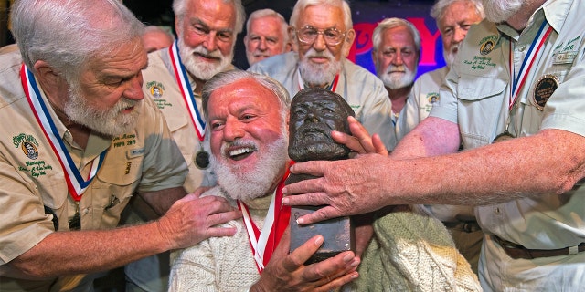 In this Saturday, July 23, 2022, photo provided by the Florida Keys News Bureau, Jon Auvil (center) receives an Ernest Hemingway bust and congratulations after he won the 2022 Hemingway Look-Alike Contest at Sloppy Joe's Bar in Key West, Fla.