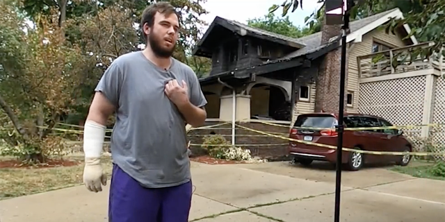 Nick Bostic em frente a uma casa que pegou fogo na segunda-feira.  Bostic correu para a casa em chamas e conseguiu ajudar a salvar quatro crianças e um adulto.