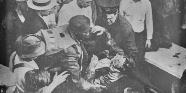Garrett A. Morgan lifts a tunnel worker from the 1916 Lake Erie crib disaster that killed 21 men. Morgan, along with his brother Frank and two other men wearing his newly patented gas mask, descended into a methane-filled hole beneath the lake bed to find survivors and remove bodies. His gas mask can be seen pulled back off his head and hanging around his shoulders.
