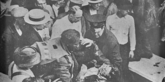 Garrett A. Morgan lifts a tunnel worker from the 1916 Lake Erie crib disaster that killed 21 men. Morgan, along with his brother Frank and two other men wearing his newly patented gas mask, descended into a methane-filled hole beneath the lake bed to find survivors and remove bodies. His gas mask can be seen pulled back off his head and hanging around his shoulders.