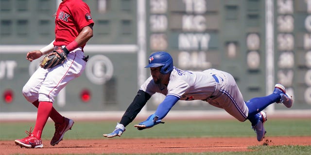 Toronto Blue Jays' George Springer, right, advances to third as Boston Red Sox's Xander Bogaerts, left, waits for the ball in the first inning of a baseball game, Sunday, July 24, 2022, in Boston.