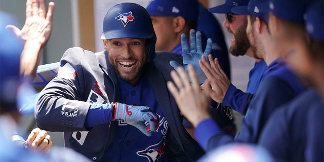 Toronto Blue Jays' George Springer wears the team's traditional home run jacket as he celebrates with teammates in the dugout after he hit a solo home run during the first inning of a baseball game against the Seattle Mariners, Sunday, July 10, 2022, in Seattle. 