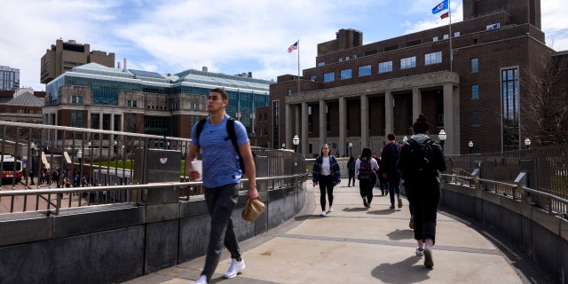 Chodec prochází kolem kampusu University of Minnesota v Minneapolis.