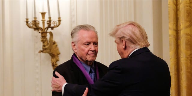 DOSSIER – Le président Donald Trump embrasse l'acteur Jon Voight après lui avoir remis la Médaille nationale des arts dans la salle Est de la Maison Blanche à Washington, DC, le 21 novembre 2019. 
