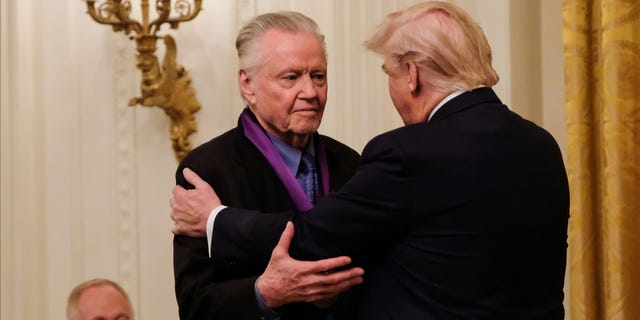FILE - President Donald Trump embraces actor Jon Voight after presenting him the National Medal of Arts in the East Room of the White House in Washington, D.C., Nov. 21, 2019.