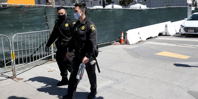 San Francisco County Sheriff's Office deputies pass by a sanctioned and fenced-in homeless encampment across from City Hall in San Francisco, Calif., on May 19, 2020.