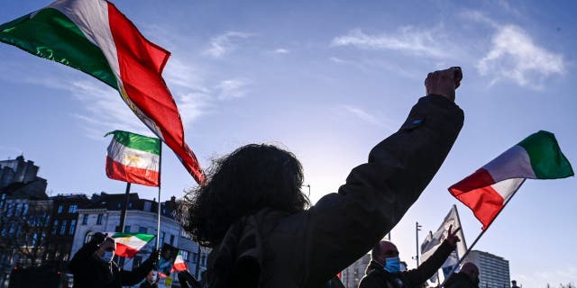 People gesture and wave former flags of Iran as they protest outside the Antwerp criminal court during the trial of four persons including an Iranian diplomate and Belgian-Iranian couple in Antwerp.