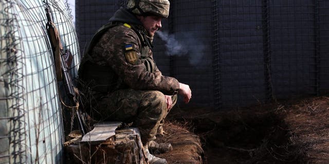 우크라이나 군인이 2022년 2월 22일 루간스크 지역의 트로이츠케 정착촌 근처에서 러시아의 지원을 받는 분리주의자들과 함께 최전선에서 담배를 피우고 있다.