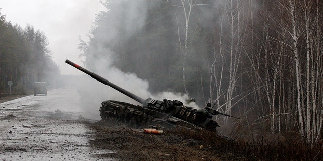 Smoke rises from a Russian tank destroyed by Ukrainian forces on the side of a road in the Lugansk region.