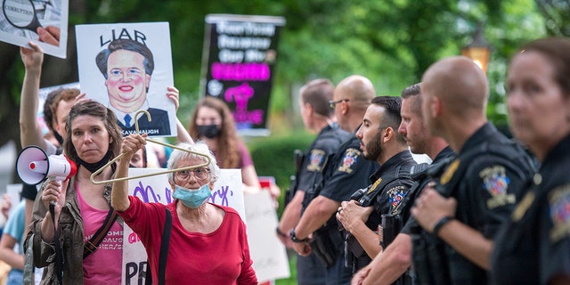 Police officers look on as abortion-rights advocates hold a demonstration outside the home of U.S. Supreme Court Justice Brett Kavanaugh.
