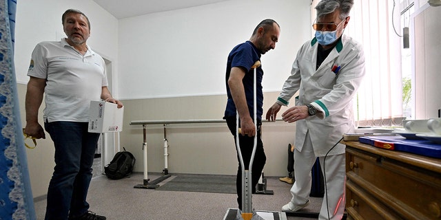Daviti Souleymanishvili, 43, born in Georgia and a naturalized Ukrainian, listens to a doctor at an orthopedic clinic, in Kyiv on May 25, 2022.