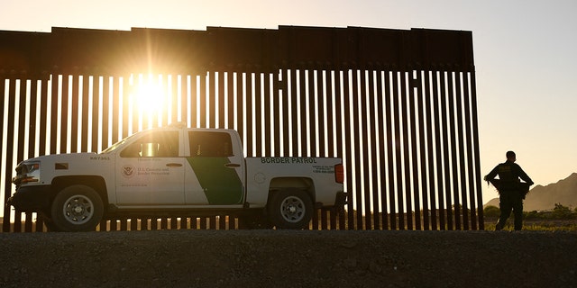 A Border Patrol agent walks between a gap along the border wall between the US and Mexico in Yuma, Arizona on June 1, 2022. 