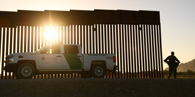 A Border Patrol agent walks between a gap along the border wall between the US and Mexico in Yuma, Arizona on June 1, 2022.