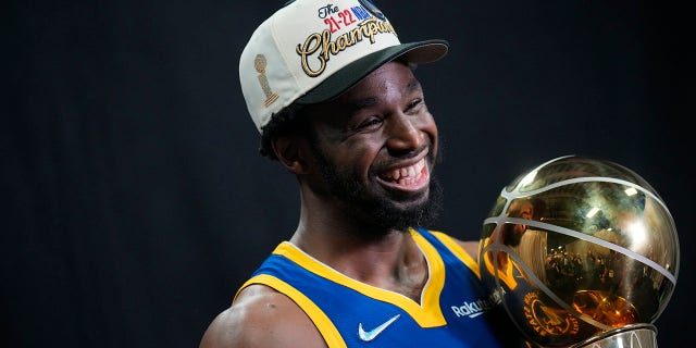 Andrew Wiggins, #22 of the Golden State Warriors, poses for a portrait with the Larry O'Brien Championship Trophy after winning Game Six of the 2022 NBA Finals on June 16, 2022 at TD Garden in Boston, Massachusetts.