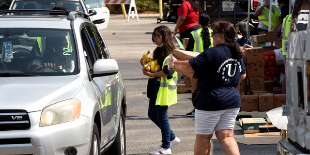 Volunteers provide bananas and other food items to the needy at a food distribution event in June 2022 sponsored by the Second Harvest Food Bank of Central Florida and Orange County at St. John Vianney Church in Orlando, Florida. High food and gas prices are squeezing working families, sending some to food pantries for the first time.