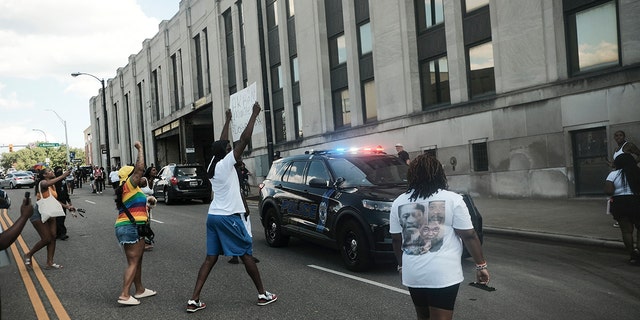 Demonstrators wave signs around a police car outside City Hall to protest the killing of Jayland Walker, shot by police, in Akron, Ohio, July 3, 2022.
