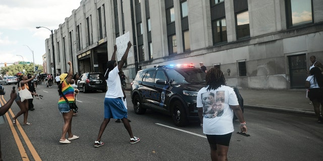 Demonstrators wave signs around a police car as they gather outside Akron City Hall to protest the killing of Jayland Walker, shot by police, in Akron, Ohio, July 3, 2022. 